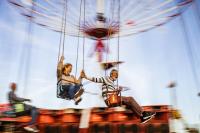Carefree mature couple holding to each other and having fun during chain swing ride at amusement park. Blurred motion.