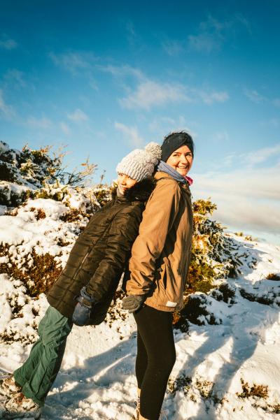 Mother and daughter leaning against one another in the snow.