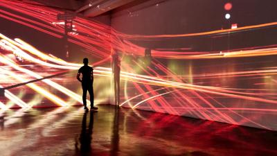 Young man looking at abstract city landscape being projected in a gallery space