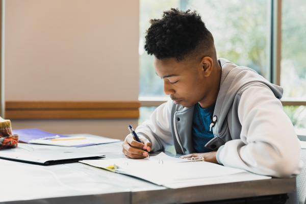 The teenage boy studies by himself in class.