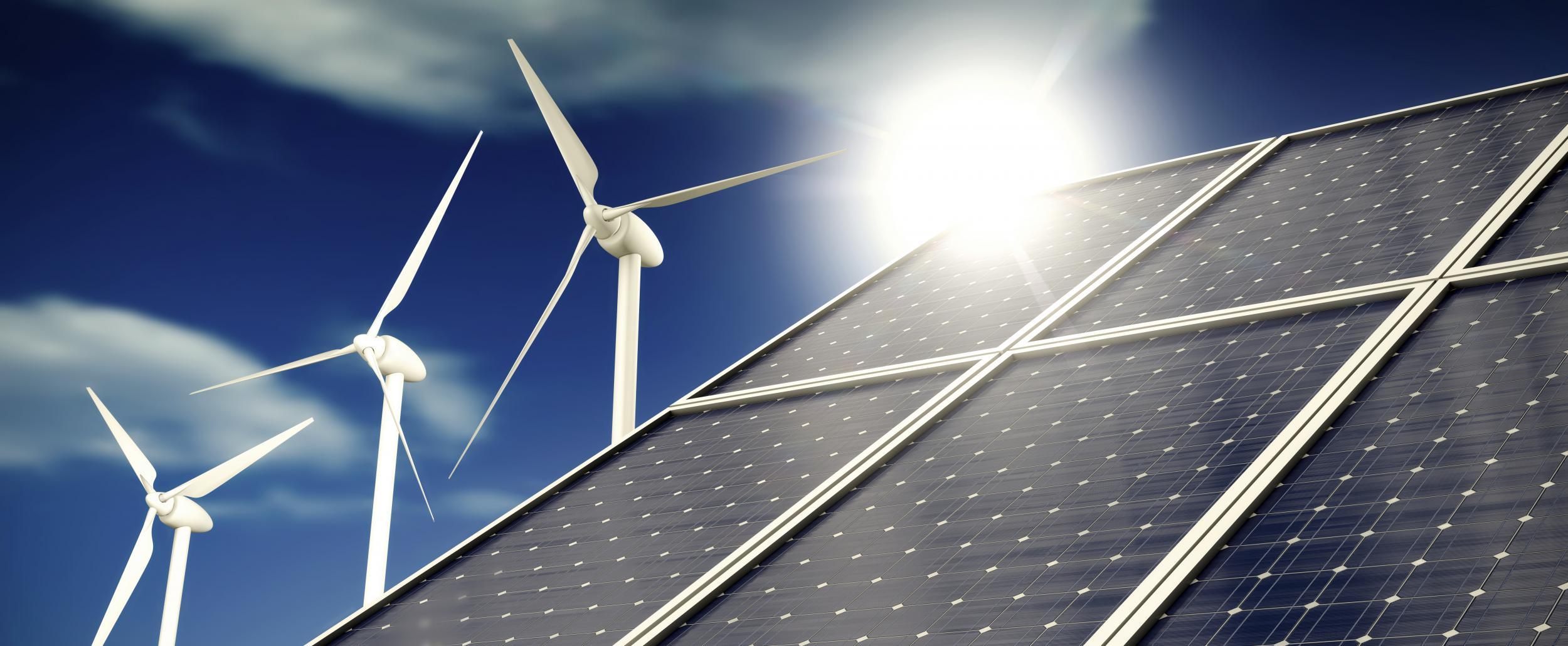 Solar panels or collectors and wind turbines infront of blue sky with clouds in sunlight