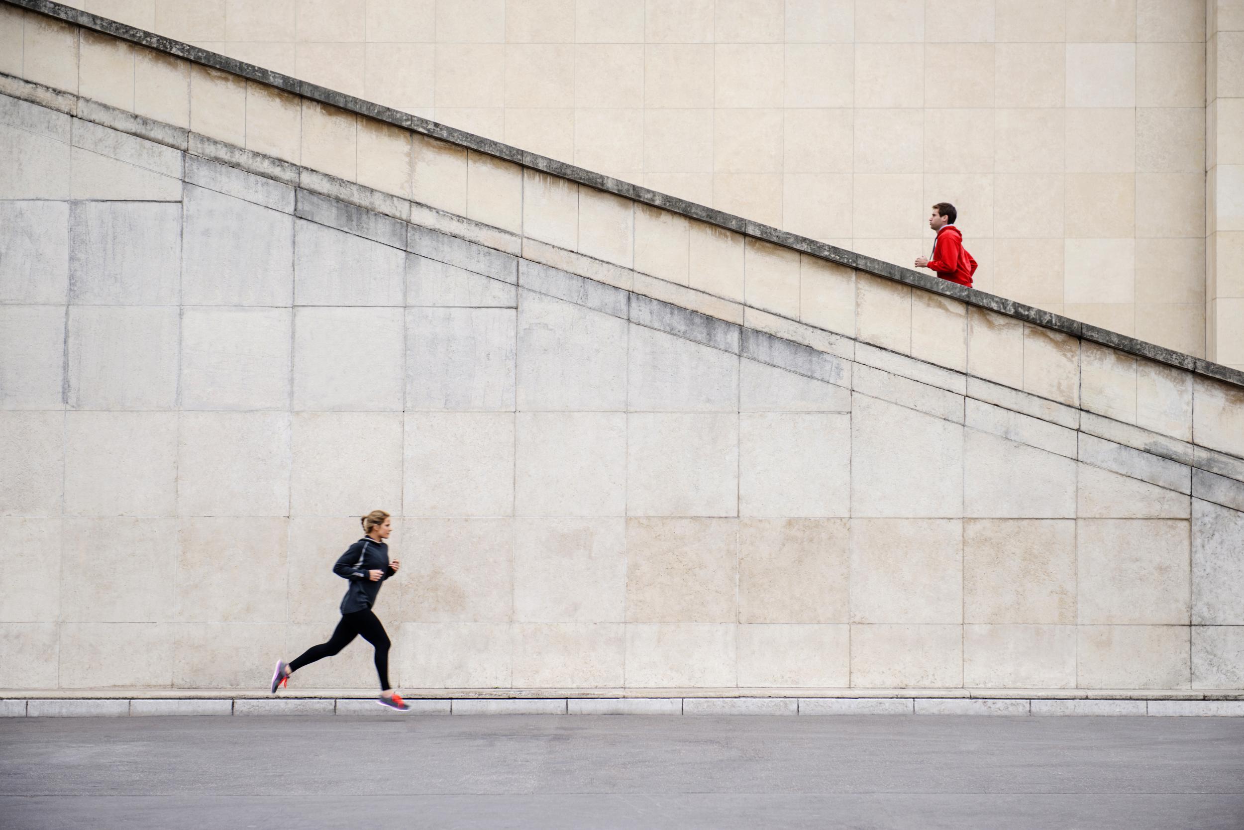 Caucasian runners jogging near staircase