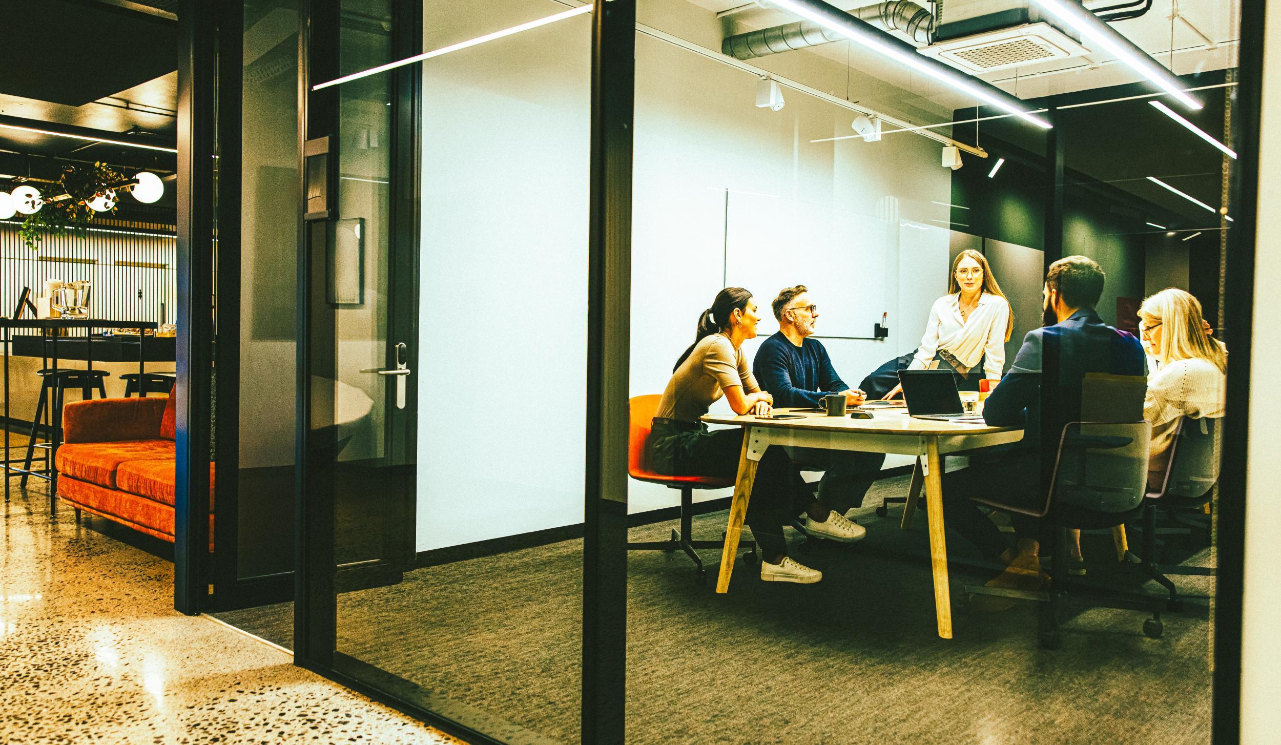 Team of businesspeople having a meeting in a b... Team of diverse businesspeople having a meeting in a transparent boardroom. Group of business professionals having a discussion during a briefing. Colleagues collaborating on a new project.
